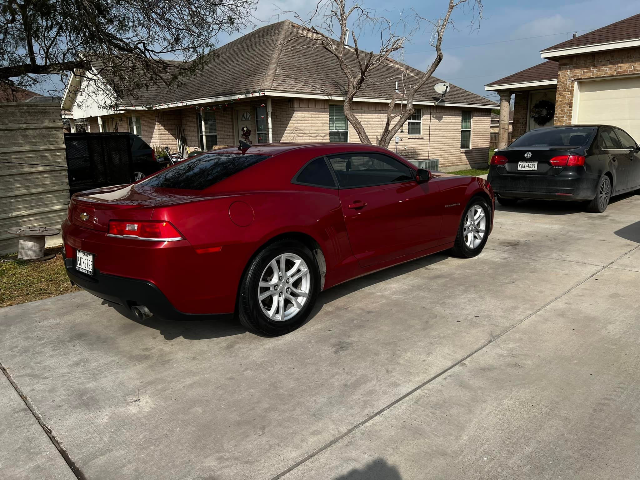 Deep red Camaro coupe, rear three-quarter, paint reflecting the sky after a full detail