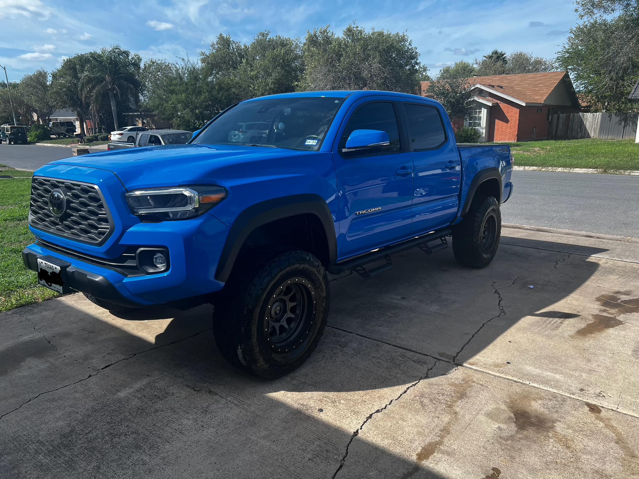 Bright blue lifted Tacoma parked on a detailed driveway
